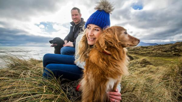 Man and Woman with two dogs on the beach at Murlough Bay