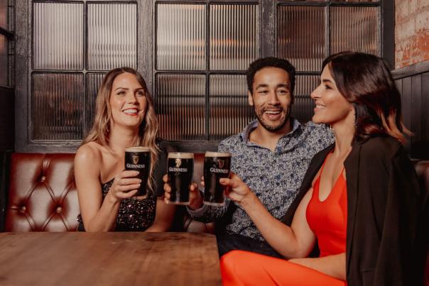 Group of three people enjoying pints of Guinness in White's Tavern & BeerHall Belfast.