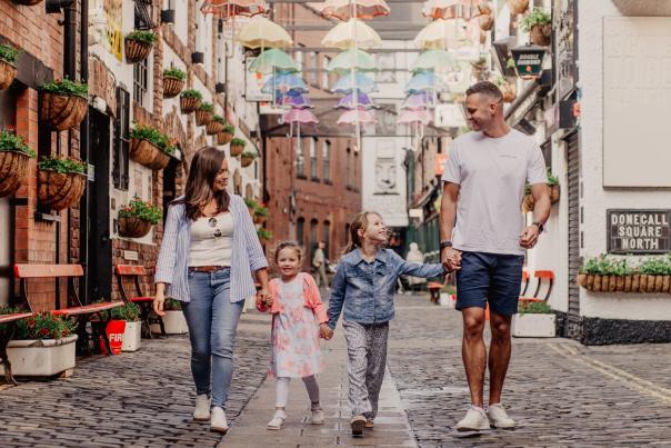 Family holding hands walking through commercial court in Belfast