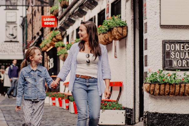 Mother and daughter holding hands walking through Commercial Court in Belfast
