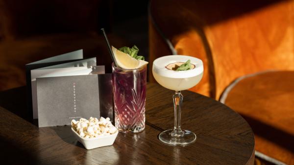 Two cocktails and a bowl of popcorn on a table at The Observatory
