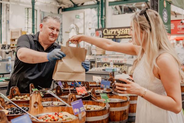 Woman buying some food goods from a seller at St George's Market