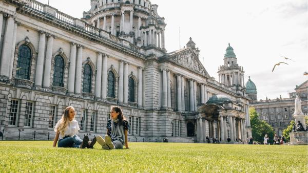 Two young women sitting on the front lawn at Belfast City Hall