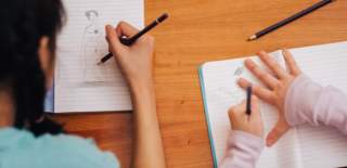 Two children drawing in notebooks