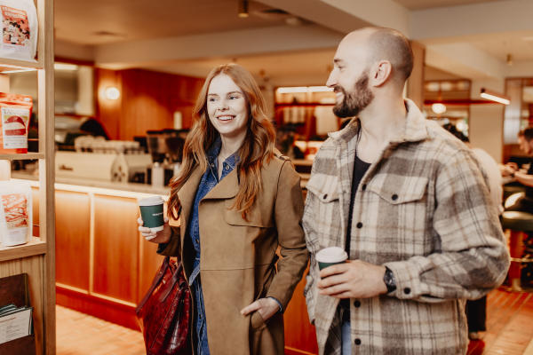 Couple walking through coffee shop with takeway coffees