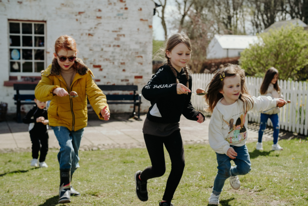 Four children having an egg and spoon race during Easter celebrations.